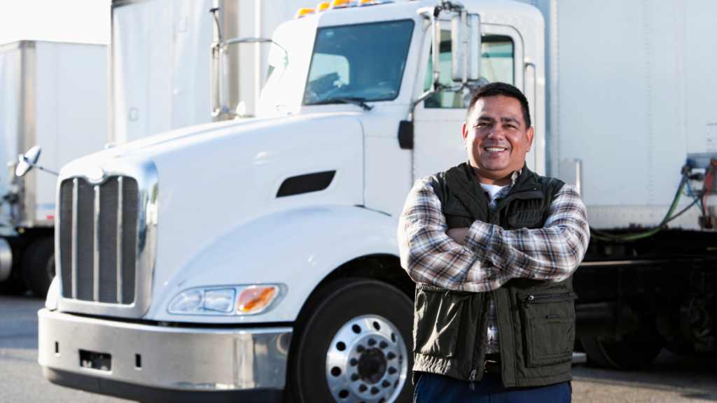 homem caminhoneiro sorrindo com um caminhão no fundo